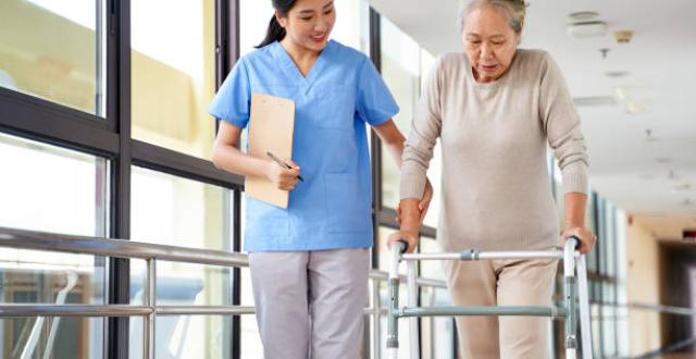 Personne âgée qui réapprend à marcher avec l'aide d'une kinésithérapeute